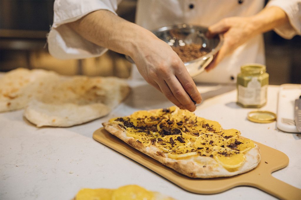 A chef topping par-baked pizza crusts.