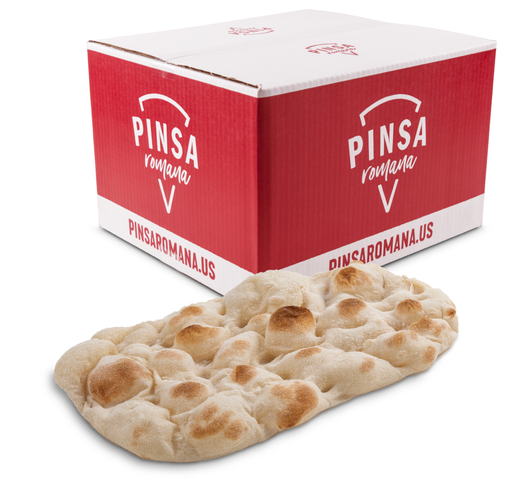 A par baked pinsa crust next to a pinsa box.
